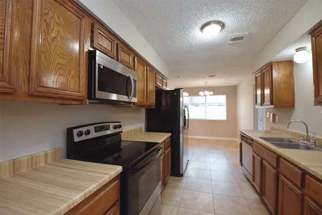 a kitchen with stainless steel appliances granite countertop a sink a stove top oven a refrigerator with wooden cabinets and floor