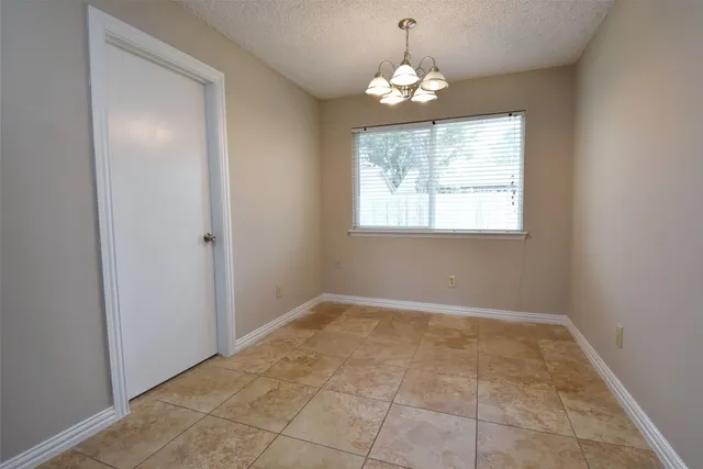 an empty room with chandelier fan and windows