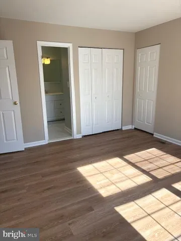 a view of an empty room with wooden floor and closet