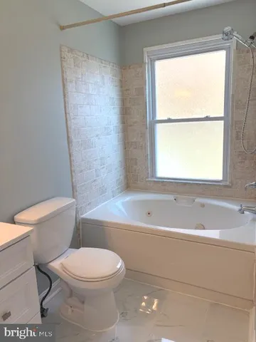 a bathroom with a toilet a bath tub and a window