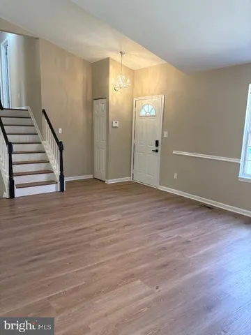a view of an empty room with wooden floor and stairs