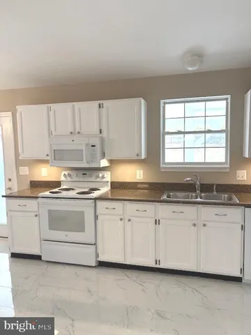 a large kitchen with granite countertop white cabinets and a sink