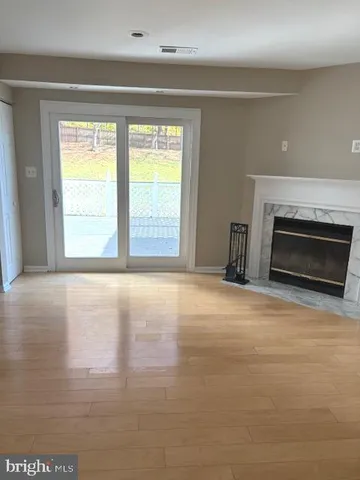 a view of empty room with wooden floor and fireplace