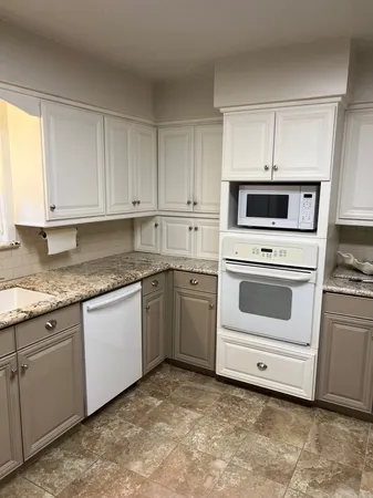 a kitchen with granite countertop white cabinets and white appliances