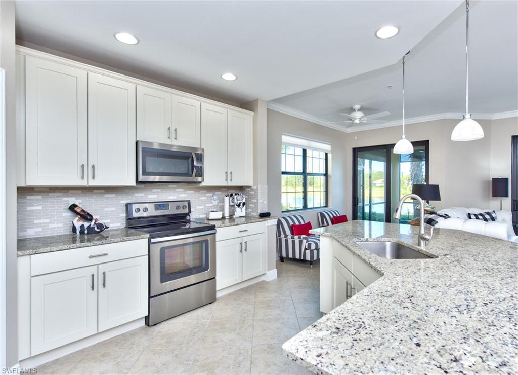 10470 Casella Way, Unit 101 Fort Myers, FL 33913 - Photo 2 of 34 a kitchen with stainless steel appliances kitchen island granite countertop a sink dishwasher stove and white cabinets with wooden floor