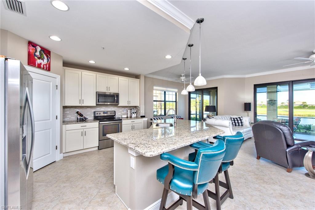 10470 Casella Way, Unit 101 Fort Myers, FL 33913 - Photo 3 of 34 a kitchen with granite countertop kitchen island stainless steel appliances a stove a sink a microwave a dining table and chairs