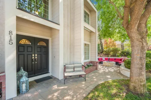 a view of a white house with a small yard and large tree
