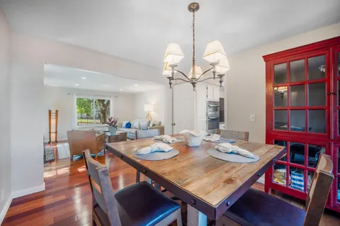 a view of a dining room and livingroom with furniture wooden floor a rug a potted plant and a chandelier