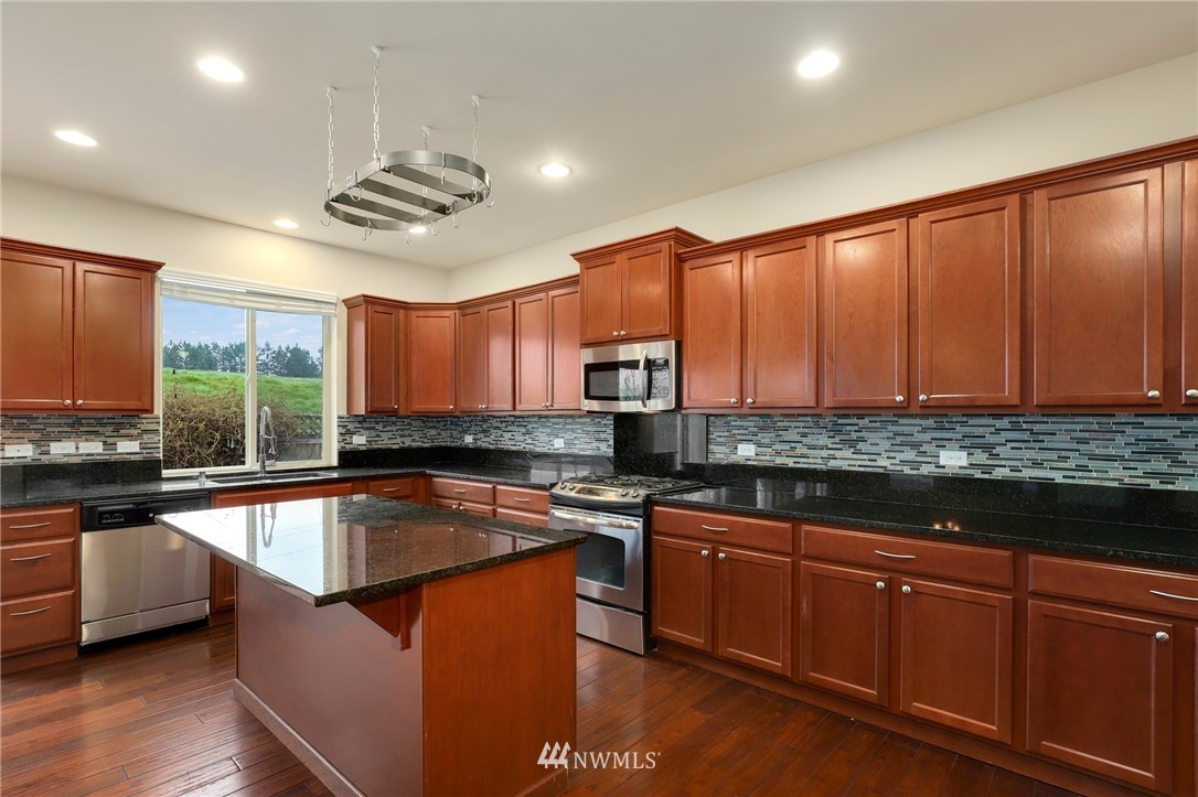 7301 Radius Loop Southeast Lacey, WA 98513 - Photo 11 of 39 a kitchen with stainless steel appliances granite countertop a sink a stove and a refrigerator