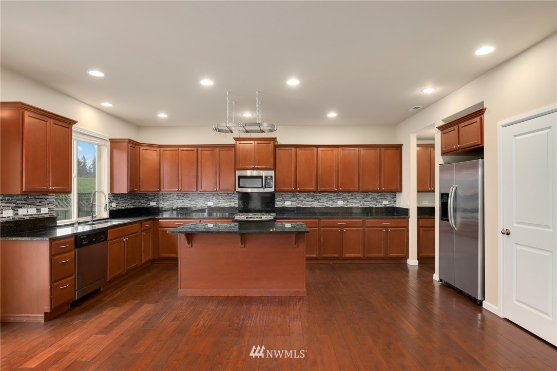 7301 Radius Loop Southeast Lacey, WA 98513 - Photo 13 of 39 a kitchen with stainless steel appliances granite countertop a refrigerator a sink dishwasher a stove and a refrigerator with wooden floor
