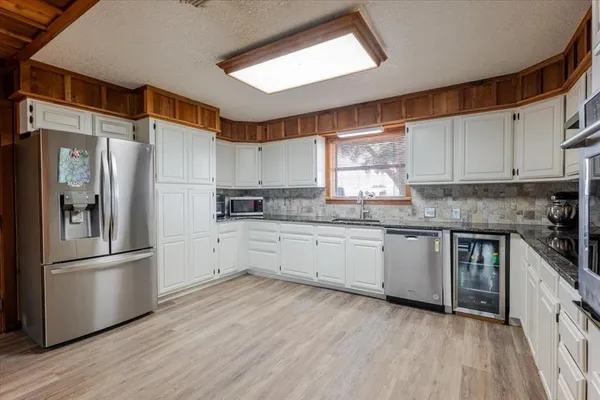 a kitchen with granite countertop a refrigerator stove top oven and sink