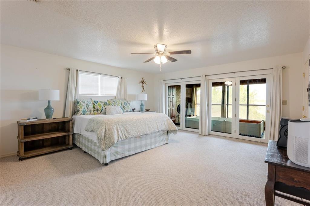 199 Willingham Loop Seymour, TX 76380 - Photo 14 of 40 a spacious bedroom with a bed and a chandelier