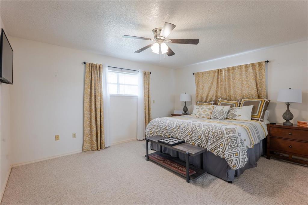 199 Willingham Loop Seymour, TX 76380 - Photo 19 of 40 a spacious bedroom with a bed and a chandelier