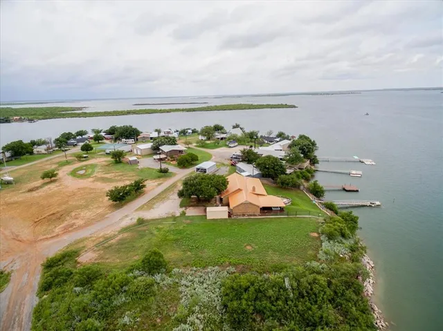 an aerial view of residential houses with outdoor space and lake view in back