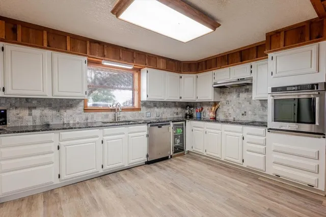 a kitchen with granite countertop white cabinets and white appliances with wooden floor