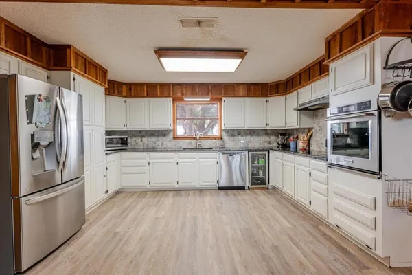 a kitchen with stainless steel appliances a refrigerator a sink and white cabinets
