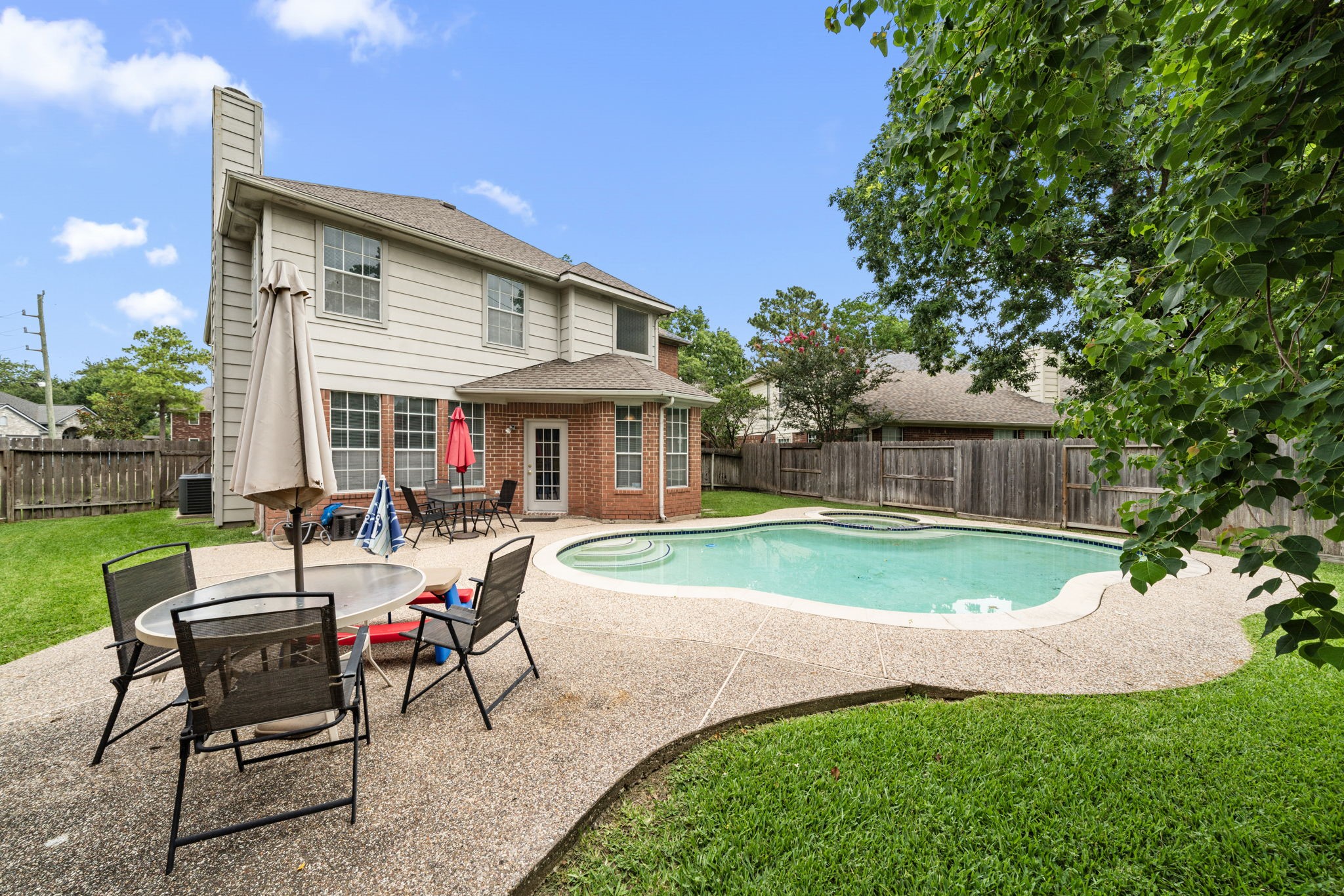 9715 Therrell Drive Houston, TX 77064 - Photo 2 of 33 The backyard includes a private swimming pool and green lawn space, all surrounded by a wooden privacy fence.