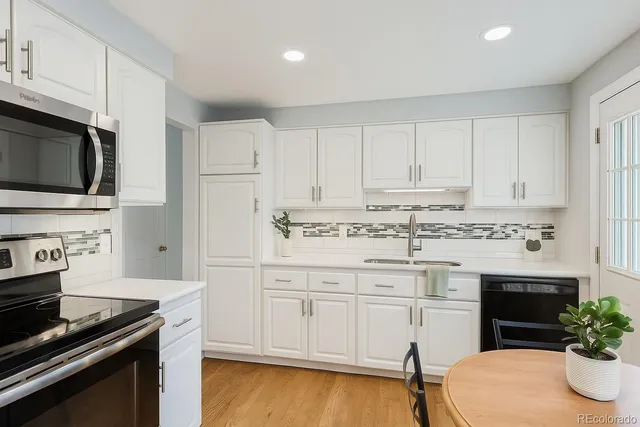 a kitchen with granite countertop white cabinets and stainless steel appliances
