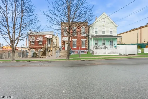 a view of a brick house with a yard and plants next to a road