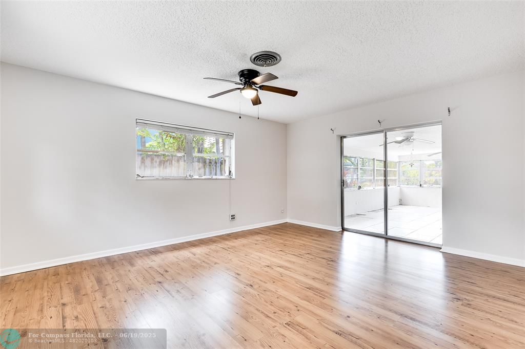 3460 Northeast 28th Avenue Lighthouse Point, FL 33064 - Photo 14 of 37 an empty room with wooden floor ceiling fan and windows