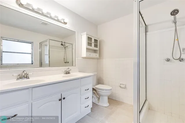 a bathroom with a double vanity sink a toilet and a mirror