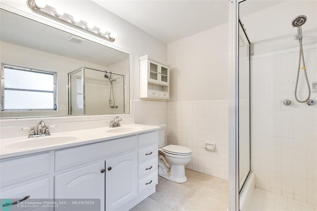 3460 Northeast 28th Avenue Lighthouse Point, FL 33064 - Photo 15 of 37 a bathroom with a double vanity sink a toilet and a mirror