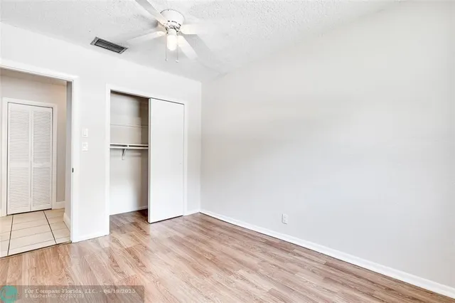 a view of empty room with wooden floor and ceiling fan