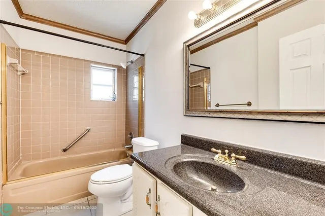 a bathroom with a granite countertop sink a toilet a mirror and bathtub