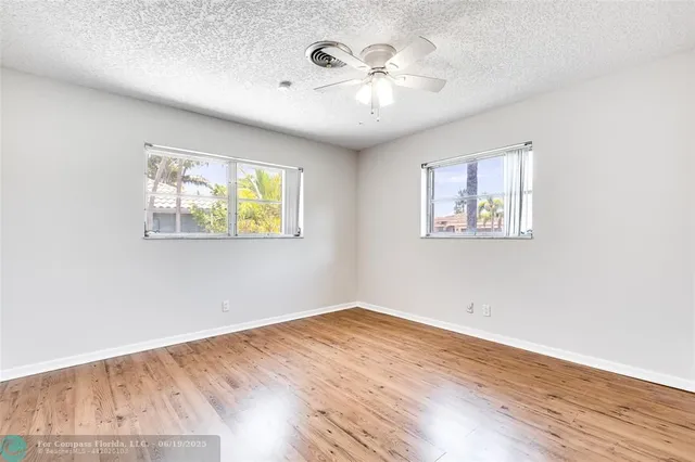 a view of empty room with wooden floor and fan