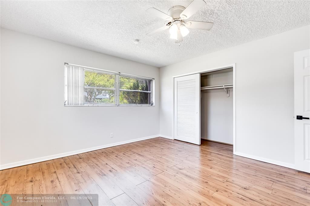 3460 Northeast 28th Avenue Lighthouse Point, FL 33064 - Photo 29 of 37 an empty room with wooden floor chandelier fan and windows