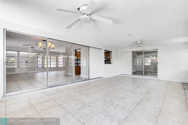 a view of an empty room with window and a kitchen
