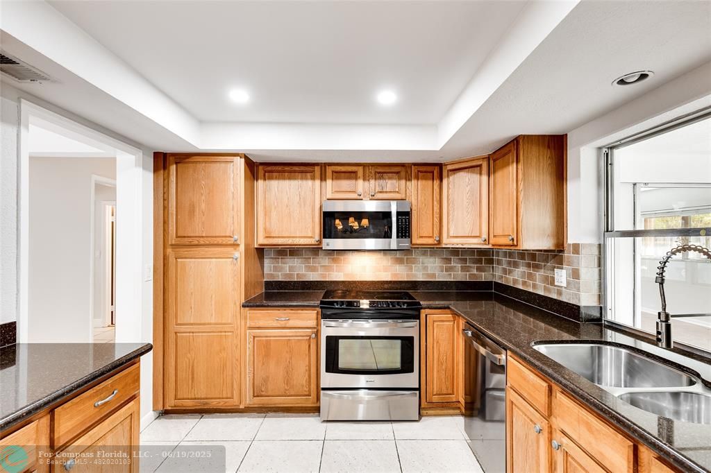 3460 Northeast 28th Avenue Lighthouse Point, FL 33064 - Photo 8 of 37 a kitchen with stainless steel appliances granite countertop a stove a sink and a microwave