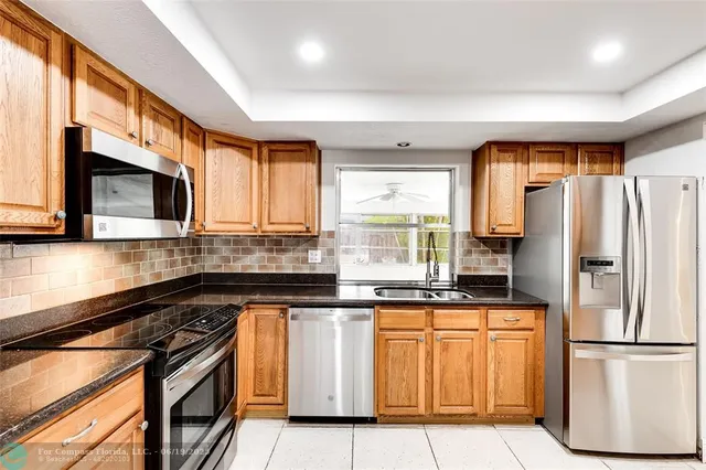 a kitchen with stainless steel appliances granite countertop a refrigerator a stove a sink and a microwave