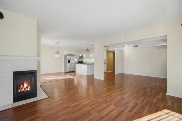 a view of an empty room with wooden floor fireplace and a window
