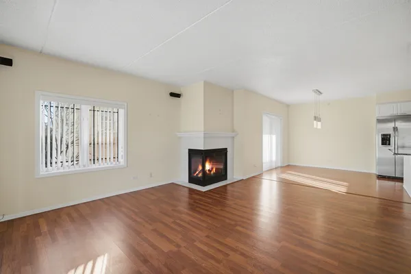 an empty room with wooden floor fire place and windows