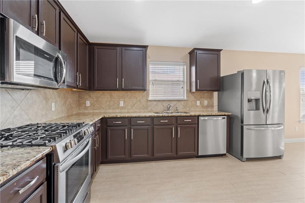 20224 Merlin Falcon Trail Pflugerville, TX 78660 - Photo 13 of 40 Culinary delights await in this modern kitchen featuring dark wood cabinetry and integrated appliances.