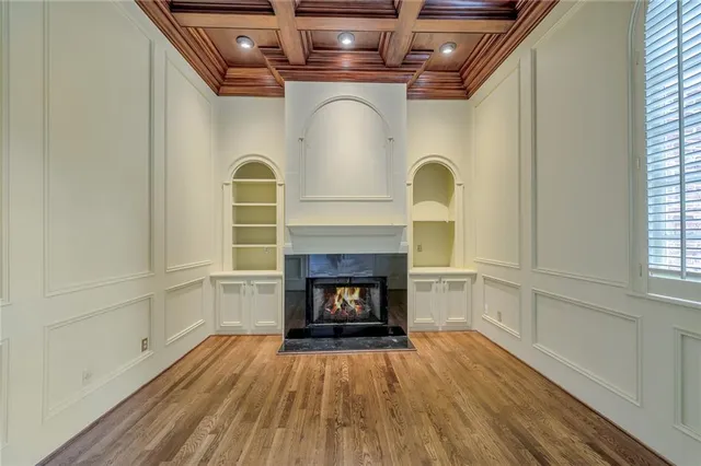 a view of an empty room with wooden floor fireplace and a window