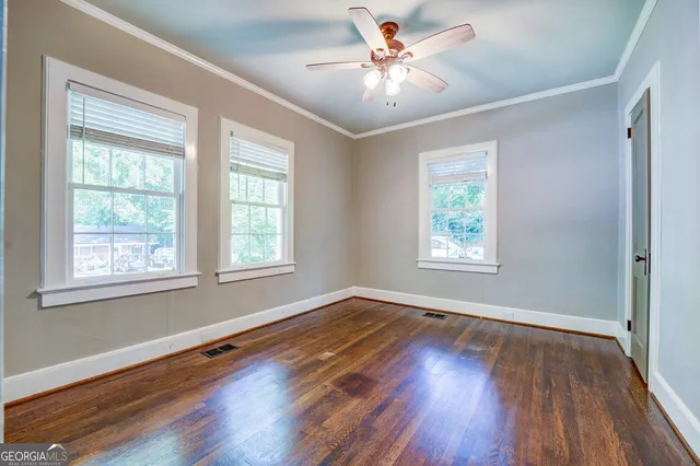 a view of an empty room with wooden floor and a window