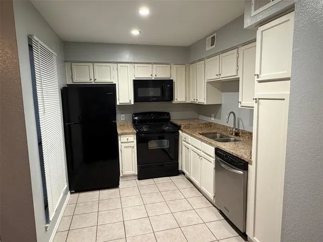 a kitchen with a refrigerator a stove top oven and cabinets
