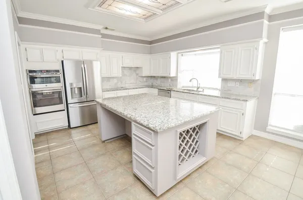 a kitchen with kitchen island granite countertop a sink stove and refrigerator