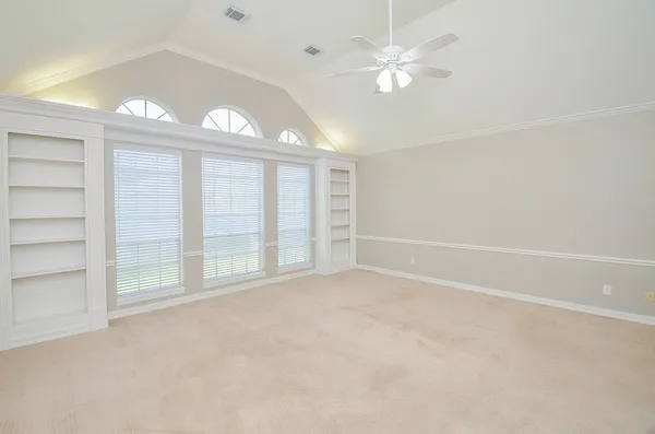 an empty room with windows and ceiling fan