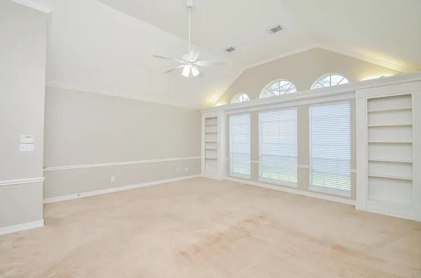 an empty room with windows and ceiling fan