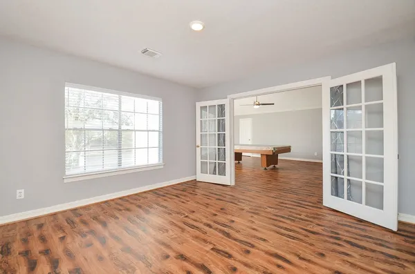 an empty room with wooden floor and windows