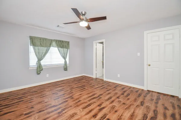 a view of empty room with wooden floor and fan