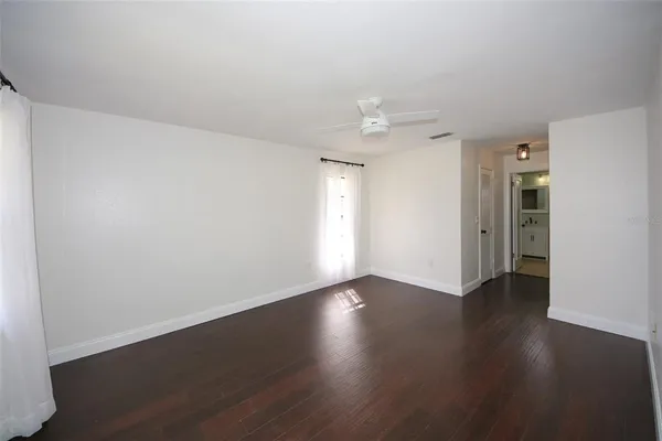 an empty room with wooden floor and windows