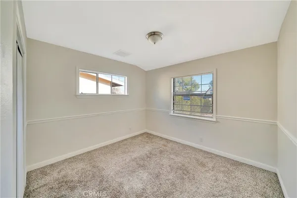 a view of an empty room with window and closet area