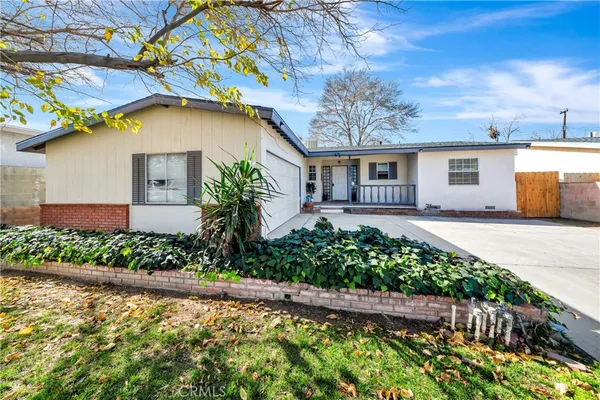 a front view of a house with garden and trees