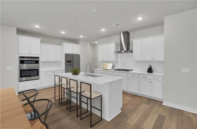 a kitchen with stainless steel appliances a sink a stove a table and chairs