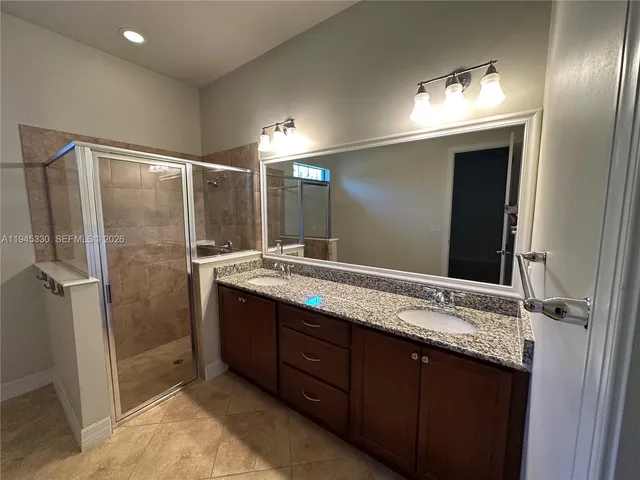 a bathroom with a granite countertop sink mirror and a shower