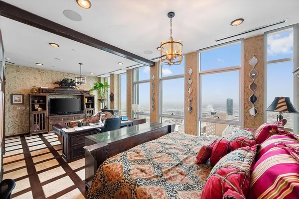 a living room with a bed a flat screen tv and a large window
